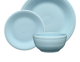 Three light blue dishes including a dinner plate, a salad plate, and a bowl, all with subtle ridged circular patterns, arranged overlapping on a white background.
