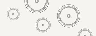 Black concentric circles of varying sizes are scattered across a plain white background, creating a minimalist, abstract pattern.