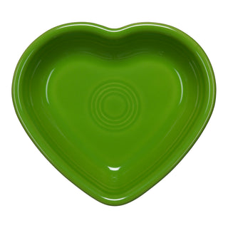 A green, heart-shaped ceramic dish with a glossy finish and concentric circles in the center, viewed from above against a white background.
