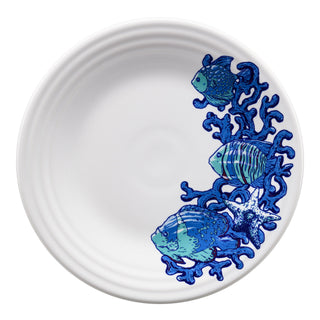 A white plate featuring a blue coral design with three blue fish and a starfish clustered along the rim.