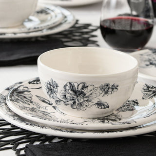 A round ceramic plate with a black and white floral design featuring detailed, hand-drawn flowers and leaves on a white background.