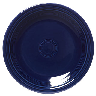 A round, dark blue ceramic plate with concentric raised rings near the rim and a glossy finish. The bottom right area shows a reflection of light.