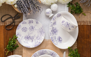 A collection of blue and white floral-patterned plates arranged in a circular pattern with a light blue mug placed on top, all set against a white background.