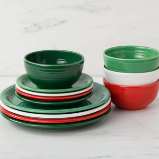 A stack of Fiesta Christmas Mixed Color Bistro Coupe 12-Piece Dinnerware Set, Service for 4, in green, red, and white sits on marble. Nested bowls and alternating plates add festive style and the dishwasher-safe set makes cleanup simple.