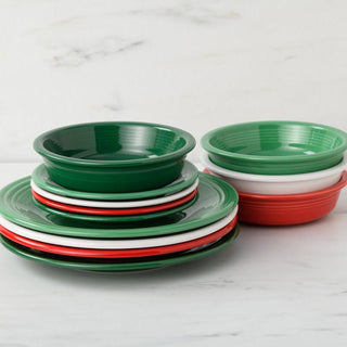 A stack of Fiesta's Christmas Mixed Color Classic Rim 12-Piece Dinnerware Set, Service for 4, in green, white, and red is arranged on a marble surface with a white marbled background.