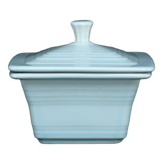 The Fiesta Retired Covered Box, measuring 4 5/8 x 3 3/4 inches, features a sky blue ceramic body with a matching lid and handle, square shape with curved sides and horizontal ridges; made in the USA.
