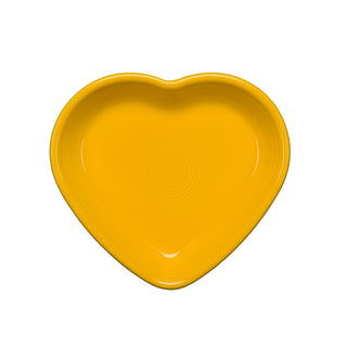 The Fiesta Retired 7 1/2 Inch Medium Heart Shaped Bowl (17 oz) in daffodil, made from lead-safe china, features glossy, smooth ceramic with concentric circle details and is shown against a white background.