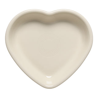 The Fiesta 7 1/2 Inch Medium Heart Shaped Bowl (17 OZ) in Linen features a smooth ceramic surface with center ridges. Proudly made in the USA, this Fiesta dish makes a thoughtful gift and is shown from above on a white background.
