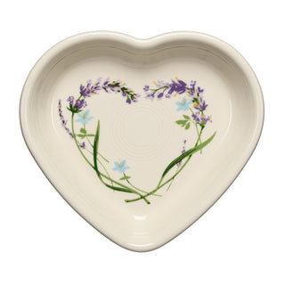 Off-white, lead-safe Fiesta Lavender Bloom 7 1/2 Inch Medium Heart Shaped Bowl 17 OZ decorated with a central heart pattern made of lavender sprigs and small blue flowers.