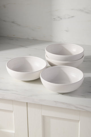 The Fiesta White Set of 4 Bistro Coupe 7 5/8-Inch 38OZ Medium Bowls is shown grouped on a marble counter. These vitrified ceramic bowls are dishwasher and microwave safe for everyday use.