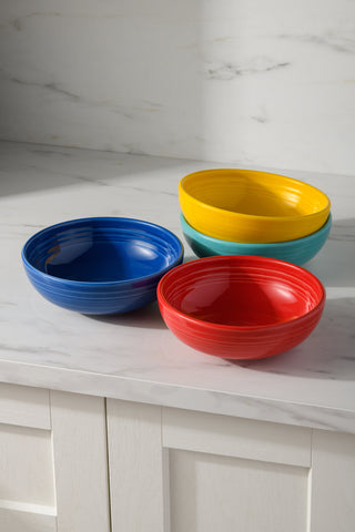 The Fiesta Mixed Vibrant Bistro Coupe 7 5/8-Inch 38OZ Medium Bowls, Set of 4, in blue, red, yellow, and turquoise, brighten a white marble countertop with their bold colors and stylish design.