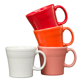The Fiesta Retired Mixed Sunset Horizon 15 OZ Set of 4 Mixed Tapered Mugs features red, orange, pink, and white glossy mugs stacked with right-aligned handles. These dishwasher-safe mugs have a simple rounded design for easy cleaning.