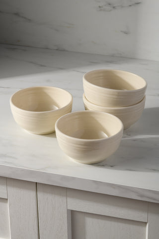 Four Fiesta Linen Bistro Coupe 5 1/2 Inch Cereal Bowls, 22 oz each, are arranged on a marble countertop—two stacked and two separate—against a light marble-patterned backsplash. Set of 4.