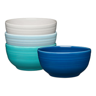 The Fiesta Mixed Coastal Blues Bistro Coupe 5 1/2 Inch Cereal Bowl set includes four 22 oz ceramic bowls in white, light blue, turquoise, and dark blue with subtle horizontal stripes. Microwave safe and stylish, they're shown stacked on a clean white background.