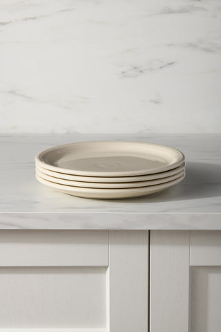 A Linen Set of 4 Bistro Coupe 10 1/2 Inch Dinner Plates by Fiesta is stacked on a marble countertop, with a white paneled cabinet below and a white marble backsplash in the background.