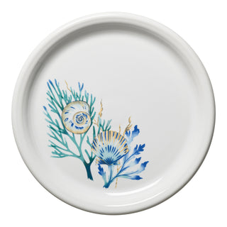The Retired Coastal Shores Bistro Coupe 10 1/2 Inch Dinner Plate by Fiesta features blue and green sea-inspired designs on white china, with coral, seaweed, and seashell accents painted on one side. Made in the USA.