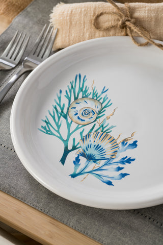 The Fiesta Retired Coastal Shores Bistro Coupe 10 1/2" Dinner Plate features blue and beige seashell and coral designs on white vitrified china, shown on a gray placemat with two forks and a twine-tied beige napkin; made in the USA.