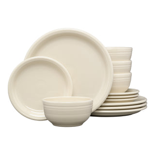 The Fiesta Bistro Coupe 12-Piece Dinnerware Set in Linen features modern, cream-hued plates and bowls neatly stacked, some upright to showcase their smooth, glossy circular design. Service for 4.