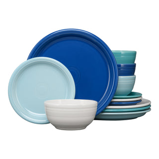 The Fiesta Mixed Coastal Blues Bistro Coupe 12-Piece Dinnerware Set, Service for 4, features plates and bowls in blue, teal, and white hues—stylishly stacked together on a white background.