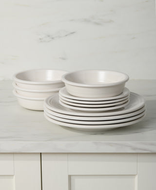 A stack of four bowls and six matching plates from the Fiesta Classic Rim 12-Piece Dinnerware Set is arranged on a marble countertop with a light-colored backsplash.