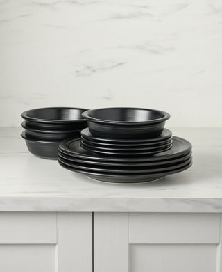 The Fiesta Classic Rim 12-Piece Dinnerware Set (Service for 4, Foundry) is stacked on a white marble countertop with a light marble backsplash and white cabinets below.