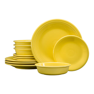 A stack of sunflower-colored Fiesta (FTC) Classic Rim 12-Piece Dinnerware Set, Service for 4, featuring plates and bowls neatly arranged against a white background—ideal for brightening any table setting.
