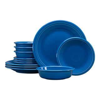The Fiesta Classic Rim 12-Piece Dinnerware Set in lapis, service for 4, features shiny blue plates and bowls neatly stacked and arranged against a white background.