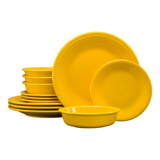 The Fiesta Classic Rim 12-Piece Dinnerware Set in daffodil features plates and bowls for four, arranged in stylish overlapping stacks against a white background for a fresh, modern look.