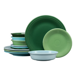 A stack of plates and bowls from the Fiesta Mixed Aegean Classic Rim 12-Piece Dinnerware Set, Service for 4, in shades of green and blue, with some arranged upright and others lying flat.