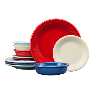 A stack of Fiesta Mixed Americana Classic Rim 12-Piece Dinnerware, with a Sky extra-large bowl, features red, white, blue, and light blue pieces arranged upright against a plain white background.