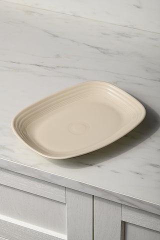 The Fiesta 12 Inch Large Rectangular Platter by Fiesta, made from lead-safe china with a ridged design, rests on a marble countertop above white cabinets.