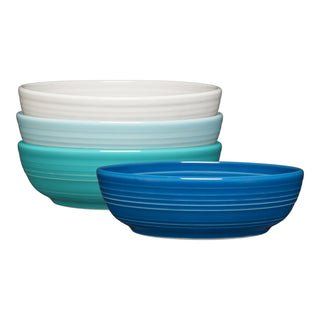 The Fiesta Mixed Coastal Blues Coupe 6 3/4 Inch Salad Bowl Set includes four 24 oz ceramic bowls in white, light blue, teal, and dark blue, each with a ribbed texture and glossy finish—perfect for a coastal kitchen.