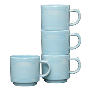 The Fiesta Sky 16 OZ Set of 4 Stackable Mug Set features light blue mugs with handles and subtle horizontal grooves near the rim—three stack for storage, while one sits in front, adding style to your coffee bar.