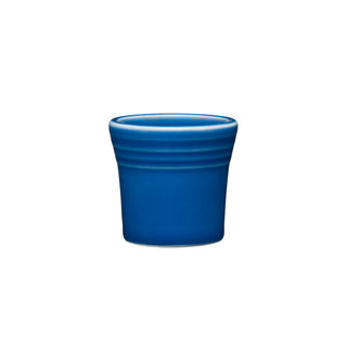 The Fiesta 1 1/2 OZ Ceramic Shot Glass by Fiesta, in lapis blue, features a small round shape with a flared rim and horizontal ridges near the top. Made in the USA and dishwasher safe, shown on a white background.