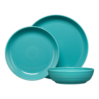The Fiesta Coupe Bowl 3-Piece Place Setting includes turquoise ceramic dishes—two plates and a coupe bowl with glossy finishes and concentric center patterns—artfully overlapped on white. Made from lead-safe china.