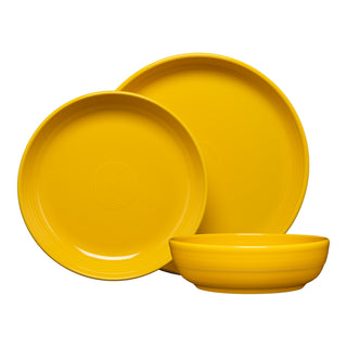 The Fiesta Coupe Bowl 3-Piece Place Setting includes a large plate, medium plate, and shallow bowl. Each piece features a glossy yellow finish with concentric circles and is crafted from lead-safe china.