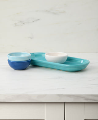 The Fiesta Coastal Blues Mixed Colors 4-Piece Condiment Set showcases a white bowl and two blue mini bowls on a stylish tray atop a marble countertop, set against a light marble wall.