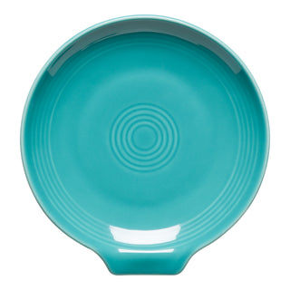 The Fiesta Extra Large Spoon Rest (7 Inch) in turquoise is a round ceramic piece with a small flat handle and concentric raised circles, perfect as a stylish kitchen utensil holder. Shown on a white background.