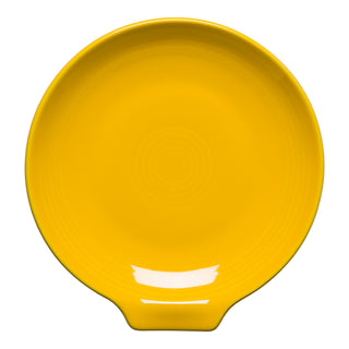 A Fiesta Retired Extra Large Spoon Rest, 7 inches in daffodil yellow, features a round shape with a small tab handle, concentric circular grooves, and a glossy finish—shown from above on a white background.