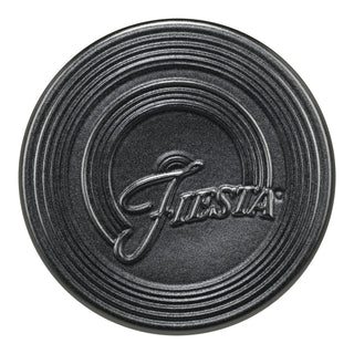 The Fiesta Foundry Extra Large Trivet (8 1/4") is a round, black ceramic trivet featuring embossed concentric rings and “Fiesta” in stylized script across the center.