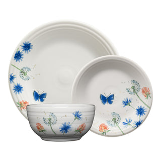 The Retired Breezy Floral Classic Bistro 3-Piece Dinnerware Set by Fiesta includes three white dishes—a plate, a bowl, and a smaller plate—each featuring blue butterflies, dandelions, and vibrant wildflowers in a delicate painted design. Every piece in this service for one showcases a unique arrangement of the floral motif and is proudly made in the USA.