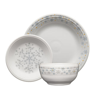 The Fiesta White Snowflakes Classic Bistro 3-Piece Dinnerware Set, Service For 1, includes a classic rim dinner plate, a salad plate, and a bistro coupe cereal bowl—each adorned with silver and gold snowflake patterns along the edges. For an elegant presentation, the lead-safe china bowl is placed in front, the salad plate to the left, and the dinner plate at the back.