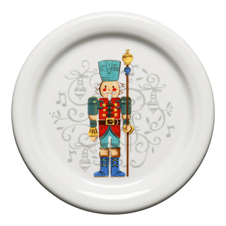 The Fiesta Nutcracker Coaster Set of 2 features a colorful nutcracker in blue and red attire, holding a staff, with musical notes and swirls decorating the background.
