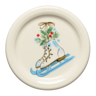 The Fiesta Jolly Christmas Skates 4 3/8" Coaster and Mug Cover features ice skates on a sled with pine, red berries, and a bow—perfect for coordinating with your seasonal tableware.