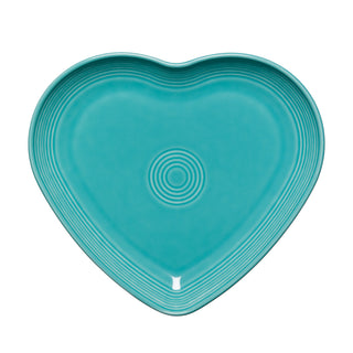 The Retired Fiesta 9 Inch Heart Shaped Plate by Fiesta is a turquoise ceramic plate with concentric circular ridges, made in the USA and shown on a white background.