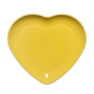 A sunflower yellow Retired Fiesta 9 Inch Heart Shaped Plate by Fiesta, featuring concentric circular grooves, shown from above on a white background. Made in the USA.