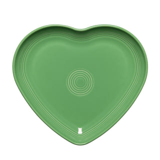 The Retired Fiesta 9 Inch Heart Shaped Plate by Fiesta, in meadow green, features concentric center circles. Made in the USA from lead-safe china, it's shown from above on a white background.