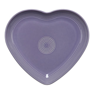 The Lavender Fiesta 9 Inch Heart Shaped Plate by Fiesta features a soft lavender finish and concentric grooves, making it a charming collector’s item when displayed against a plain white background.
