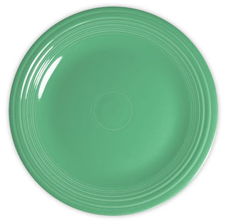 A round, solid green ceramic plate with concentric ridges near the edge, photographed from above on a white background.