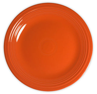 A round, bright orange ceramic plate with a glossy finish and concentric circular ridges near the rim, viewed from above on a white background.
